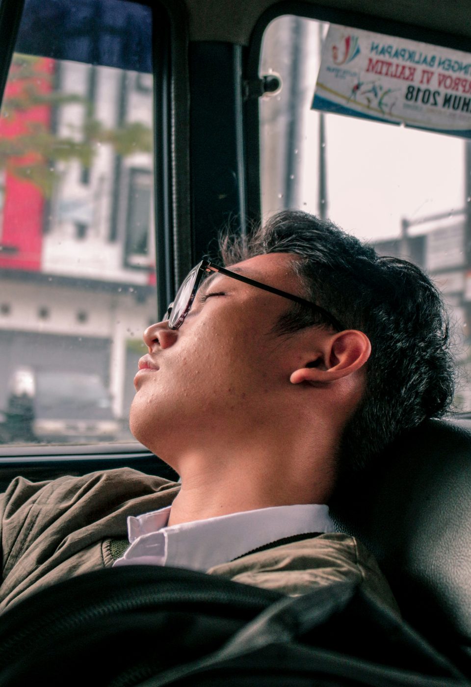 A tired commuter asleep on a jeepney